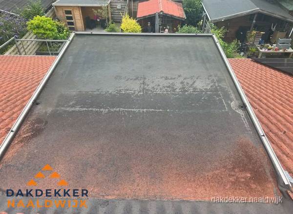 Verouderd plat dak met slijtage tussen schuine daken in Naaldwijk Verouderd plat dak met slijtage tussen schuine daken in Naaldwijk