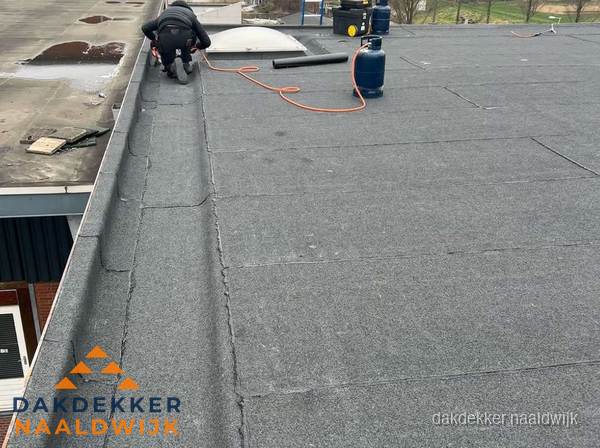 Dakdekker repareert bitumen dakbedekking op groot plat dak in Naaldwijk Dakdekker repareert bitumen dakbedekking op groot plat dak in Naaldwijk
