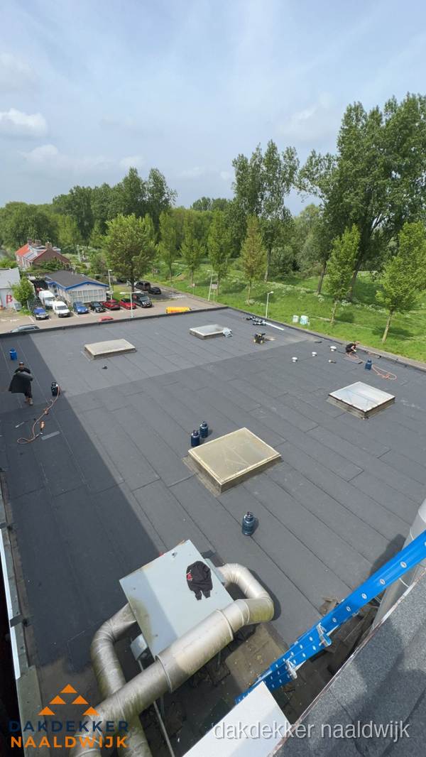 Dakdekker aan het werk op groot plat dak met bitumen in Naaldwijk