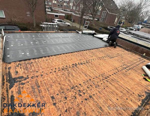 Dakdekker legt onderlaag op plat dak met houten constructie in Naaldwijk